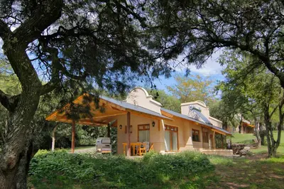 a small yellow house with a tree at Cabañas Sierra Serena in Villa General Belgrano