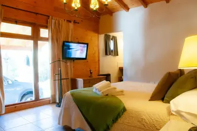 a bedroom with a bed with a tv and a window at Cabañas Sierra Serena in Villa General Belgrano