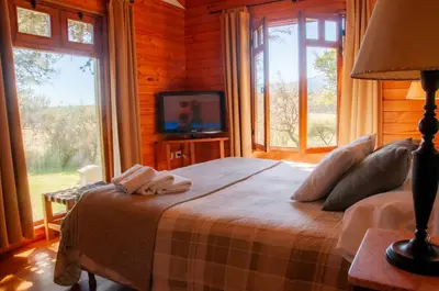 a bedroom with a bed with a tv and windows at Cabañas Sierra Serena in Villa General Belgrano