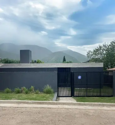 a building with a gate and mountains in the background at RumaRanch Solo Parejas Casa con pileta privada a 20 mts del Río in Villa Carlos Paz