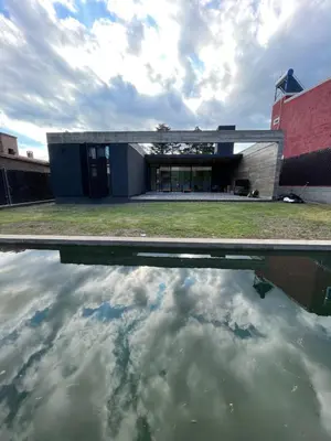 a building with a reflection in a body of water at RumaRanch Solo Parejas Casa con pileta privada a 20 mts del Río in Villa Carlos Paz