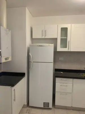 a kitchen with a white refrigerator and white cabinets at Departamento boutiques, centrico in Villa Carlos Paz