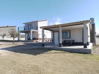 a house with a porch with a table and a balcony at Complejo El Bonsai in Villa Santa Cruz del Lago