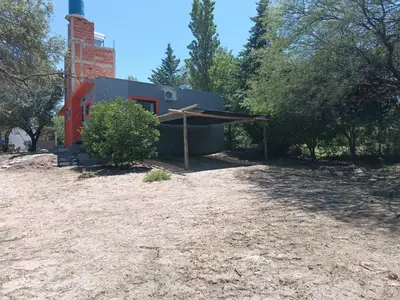 a red house with a roof on a dirt field at Barranca Poceña in Quebrada de los Pozos