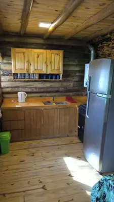 a kitchen with wooden cabinets and a stainless steel refrigerator at Cabañas lipamai in Potrero de Garay