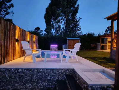 a patio with two chairs and a table and a fire place at Cabañas lipamai in Potrero de Garay