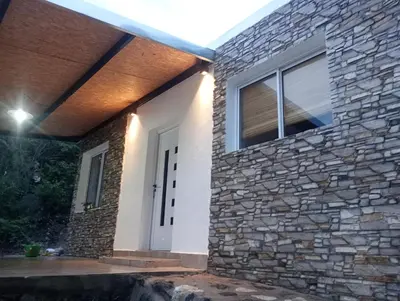 a house with a stone wall and a white door at CerroMio! in Villa Serranita