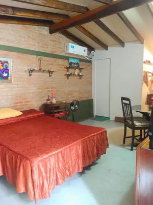 a bedroom with a red bed and a table and chairs at Mina's Apart in Mina Clavero