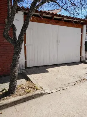 a white garage with a tree in front of it at Mina's Apart in Mina Clavero