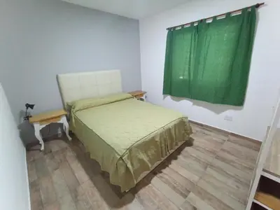 a bedroom with a bed and a green curtain at Complejo Barranca Poceña in Quebrada de los Pozos