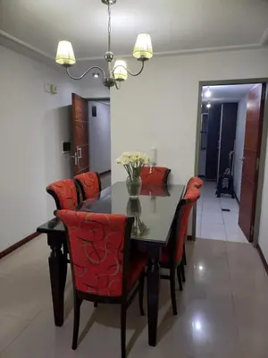 a dining room table with red chairs and a vase of flowers at MC departamento in Río Cuarto