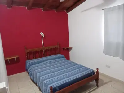 a bed in a room with a red wall at Mi Recreo in Villa Cura Brochero