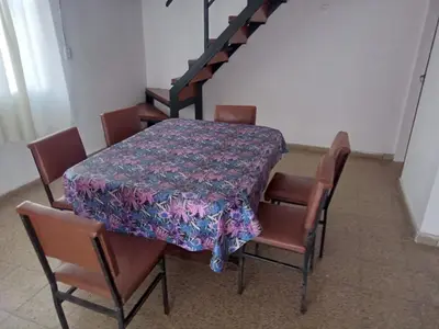 a dining room table and chairs with a flowered table and a staircase at Mi Recreo in Villa Cura Brochero