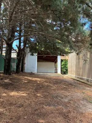 a garage with a fence and trees in a yard at Casa Q a 5km del centro de Villa Carlos Paz in Villa Santa Cruz del Lago