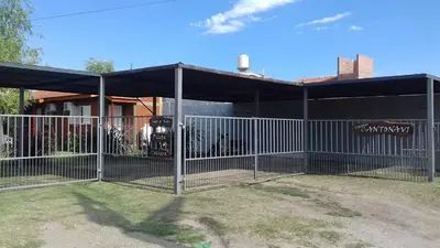 a fence in front of a building with a garage at Cantonavi Cabañas in Mina Clavero
