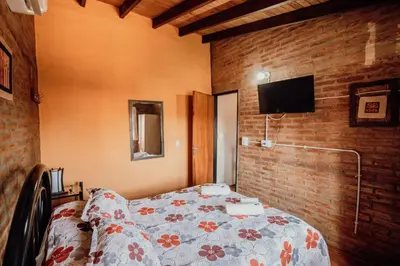 a bedroom with a bed and a tv on a brick wall at Cantonavi Cabañas in Mina Clavero