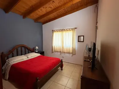 a bedroom with a red bed and a television at CASA SEN in Mina Clavero