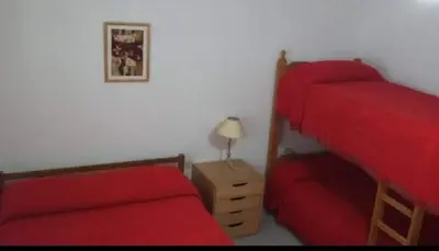 a bedroom with two bunk beds and a red bed at ARROYO SERRANO-MINA CLAVERO in Mina Clavero