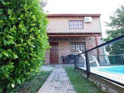 a house with a fence in front of a hedge at Dúplex PIRULO in Villa Cura Brochero