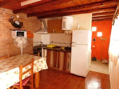 a kitchen with a table and a white refrigerator at Dúplex PIRULO in Villa Cura Brochero
