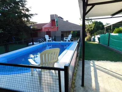 a swimming pool with two chairs sitting next to it at Dúplex PIRULO in Villa Cura Brochero