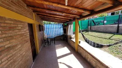 a porch with a hammock on the side of a house at Mi Recreo CABAÑAS in Villa Cura Brochero