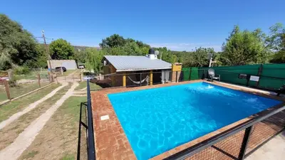 a swimming pool on a fence with a house at Mi Recreo CABAÑAS in Villa Cura Brochero