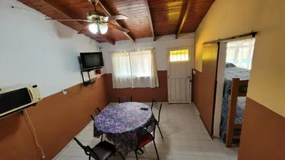 a dining room with a table and chairs and a tv at Mi Recreo CABAÑAS in Villa Cura Brochero