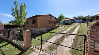 a fence in front of a house with a yard at Mi Recreo CABAÑAS in Villa Cura Brochero