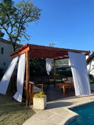 a wooden gazebo next to a swimming pool at Apartamento Remansum in Santa Rosa de Calamuchita