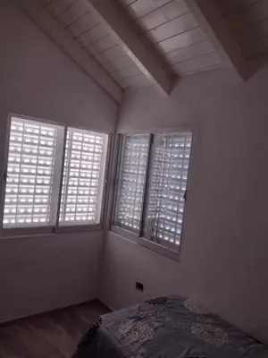a bedroom with three windows and a bed in it at El espinillo in Villa Carlos Paz