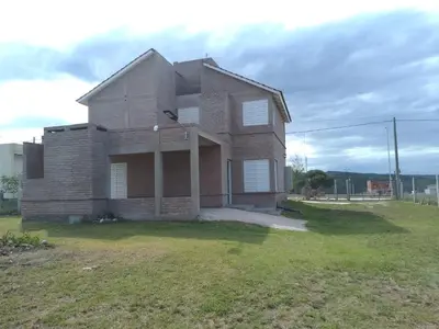 a large brick house on a grass field at El espinillo in Villa Carlos Paz