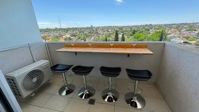 a bar with three wine glasses and stools on a balcony at Guesthouse Luxury in Cordoba
