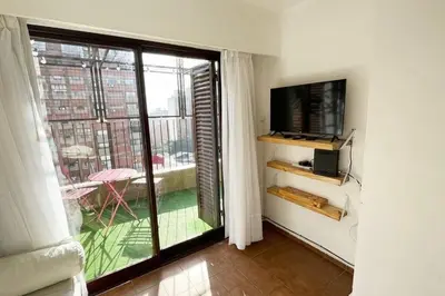 a living room with a tv and a large window at Departamento en la mejor zona de Nueva Córdoba in Cordoba
