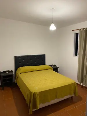 a bedroom with a bed with a yellow bedspread at departamento céntrico in Villa Carlos Paz