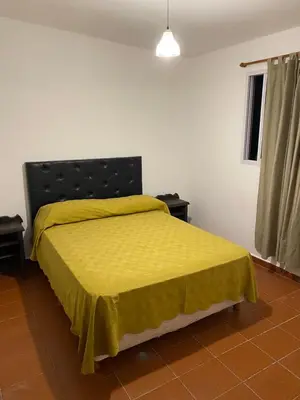 a bedroom with a bed with a yellow bedspread at departamento céntrico in Villa Carlos Paz