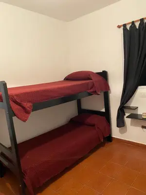 a room with two bunk beds with red sheets at departamento céntrico in Villa Carlos Paz