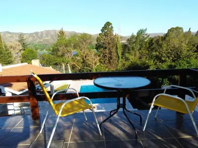 a patio with a table and chairs on a balcony at Casa con piscina vista al lago montañas-Sierras de Córdoba in Villa Parque Siquiman