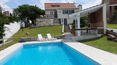 a swimming pool with two chairs and a house at Casa con piscina vista al lago montañas-Sierras de Córdoba in Villa Parque Siquiman