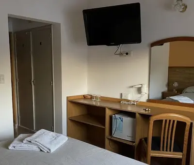 a hotel room with a desk with a television on the wall at Hotel Rossetti y Spa in Mina Clavero