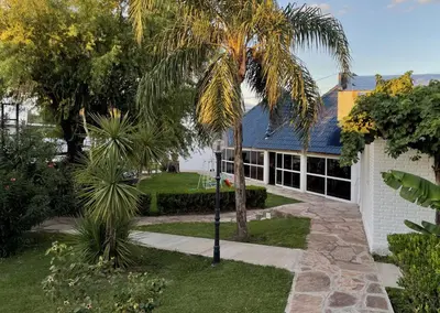 a palm tree in front of a house at Hotel Rossetti y Spa in Mina Clavero