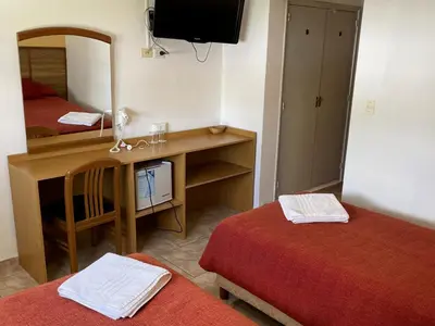 a room with two beds and a desk with a mirror at Hotel Rossetti y Spa in Mina Clavero