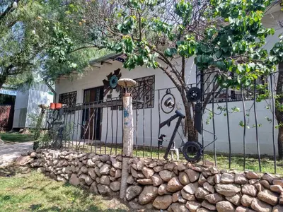 a house with a fence and a stone wall at El Escarabajo Azul loft & Arte in Villa Carlos Paz