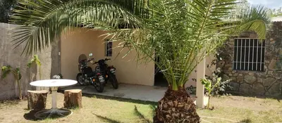 a motorcycle parked next to a house with a palm tree at Hospedaje Don Juan in Villa Dolores