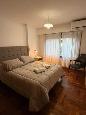 a bedroom with a large bed and a chair at Apartamento en Colón y Cañada in Cordoba