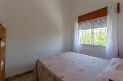a white bedroom with a bed and a window at Departamentos Valle Azul in Santa Rosa de Calamuchita