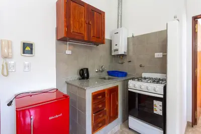 a small kitchen with a stove and a red refrigerator at Departamentos Valle Azul in Santa Rosa de Calamuchita
