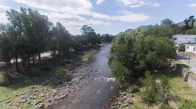 a river with trees on the side of a road at Departamentos Valle Azul in Santa Rosa de Calamuchita