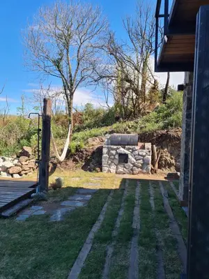 a garden with a hose on the side of a house at Chalet - Stone Cabin in Villa Icho Cruz