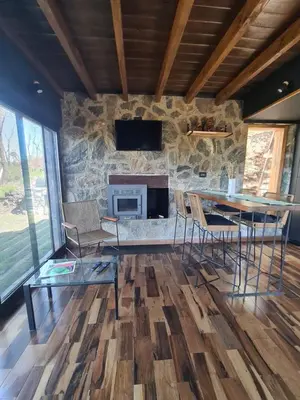 a living room with a table and a stone fireplace at Chalet - Stone Cabin in Villa Icho Cruz